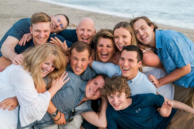A creative overhead group shot of a smiling family on the sand, capturing a joyful beach session in San Diego.
